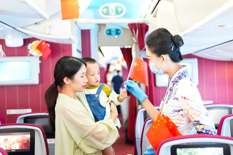 10月1日，海南航空乘務(wù)員為機(jī)上旅客發(fā)放小國旗。海南航空供圖.jpg