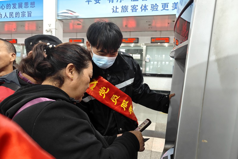 在海口站，志愿者幫助旅客購票。唐璐璐攝