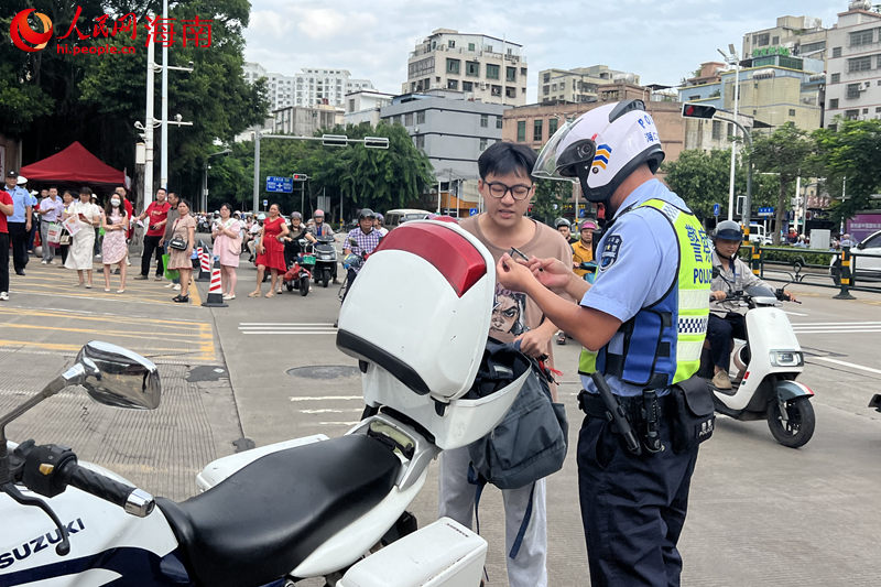 在海南省農(nóng)墾中學考點，交警載著考生取回身份證后返回考點。 人民網(wǎng)記者 李學山攝