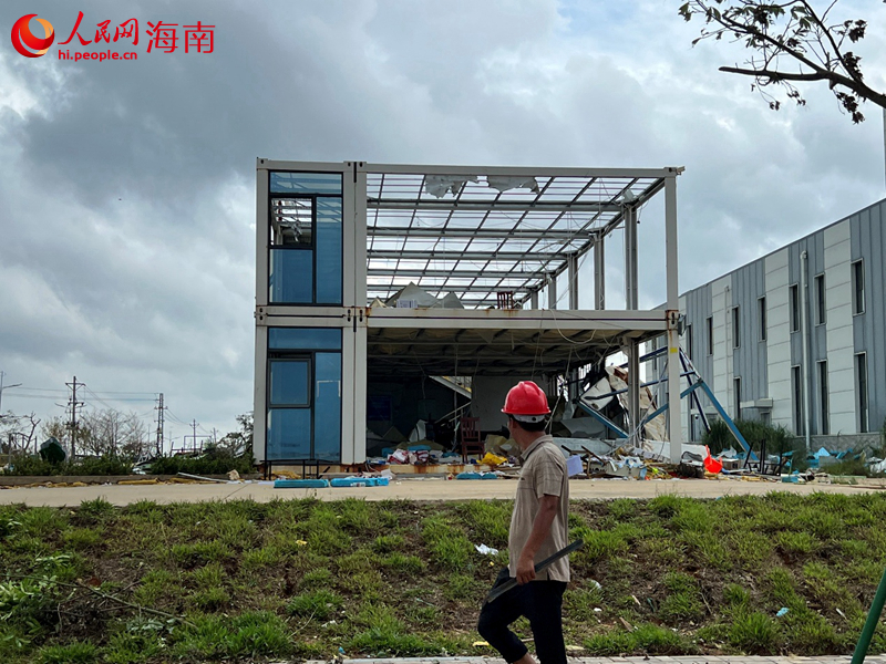 一名工人走過被臺風刮的千瘡百孔的衛(wèi)星總裝測試廠房項目部。人民網(wǎng)記者 李學山攝